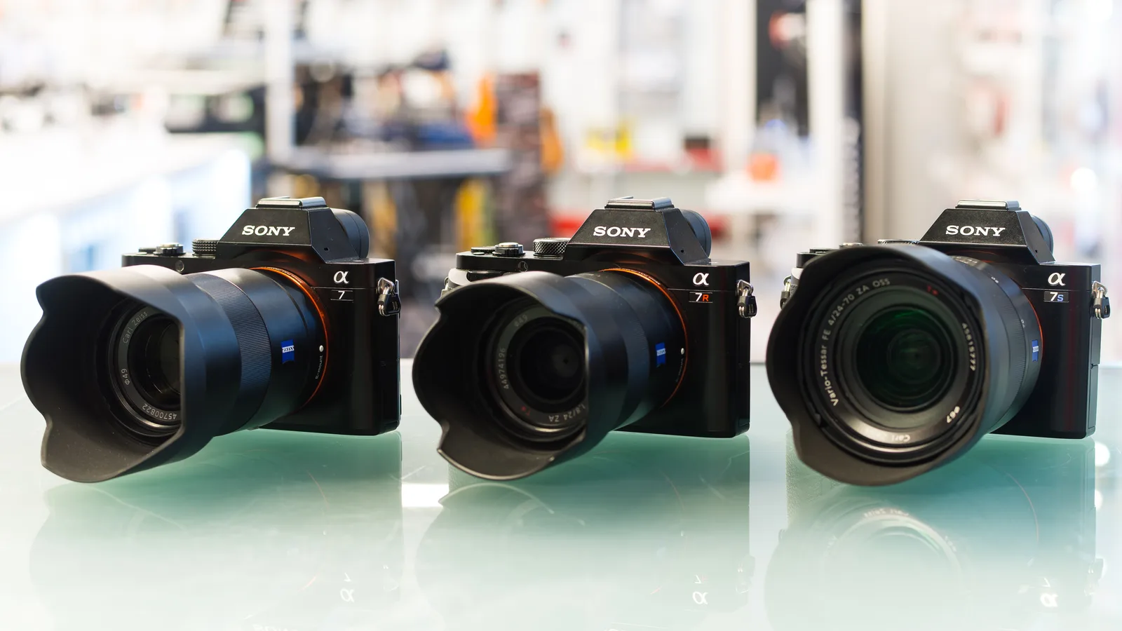 Three Sony Alpha full-frame mirrorless cameras with lenses lined up on a table