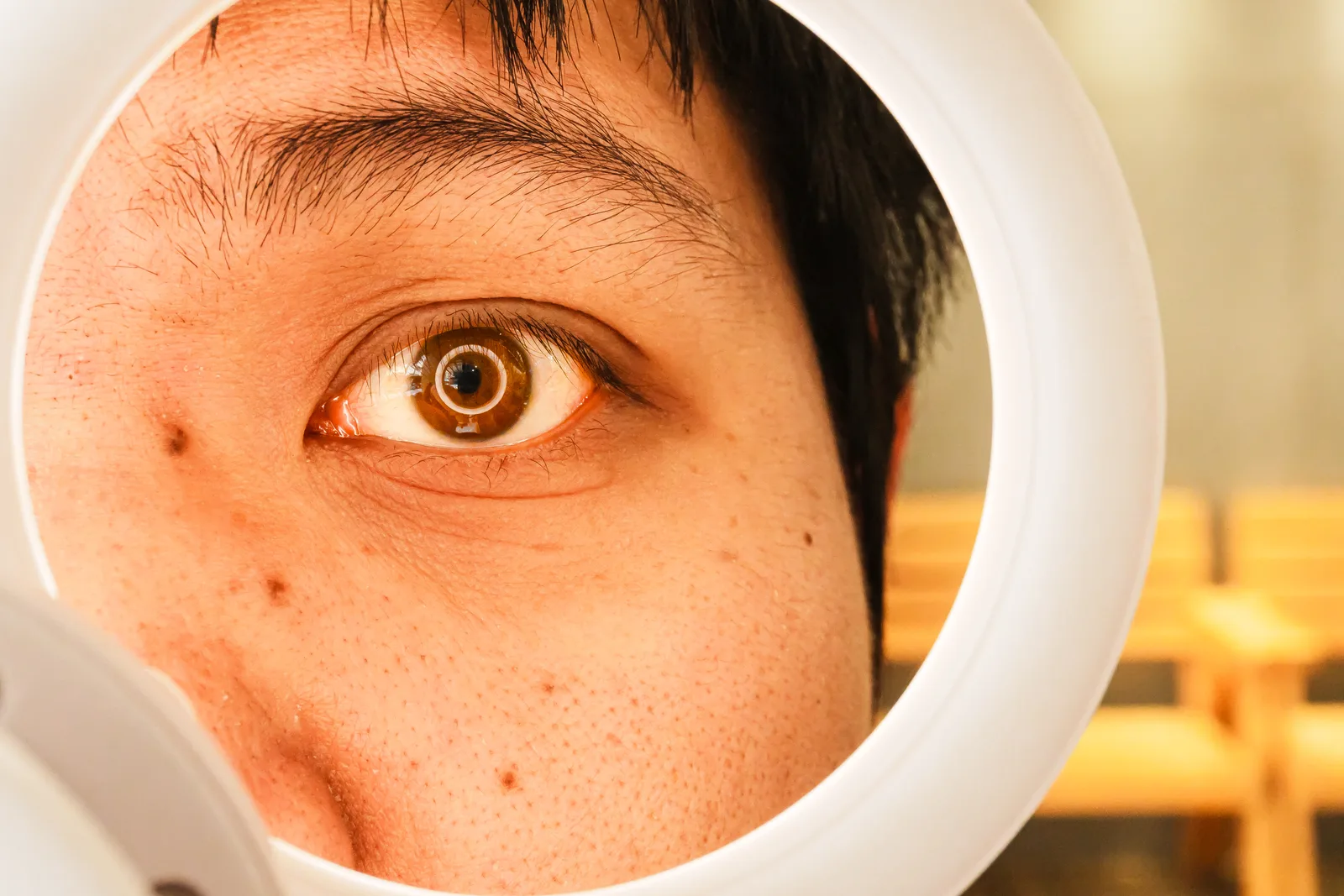 Extreme close-up of an eye with a ring light reflected as a circular catchlight in the iris